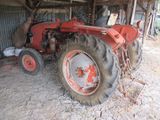 a red tractor that is parked in a barn