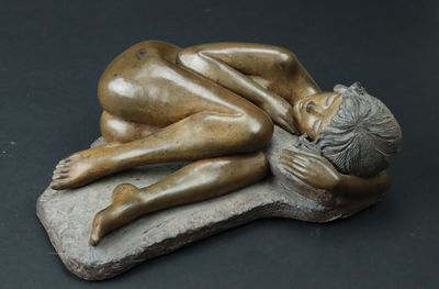statue représentant une femme allongée sur un rocher, la tête posée sur ses mains