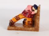 une figurine d'un homme assis sur un banc