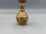 an antique brass vase on a white surface with a gray background
