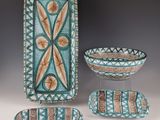 Trois pièces de poterie décorative sont exposées sur une table