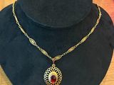 a black hat with a gold chain and a red stone pendant