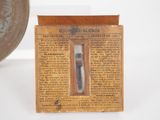 a small box with a toothbrush in it next to a coin