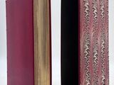two red books sitting next to each other on a white surface