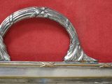 une assiette ancienne en argent avec une anse, sur fond rouge