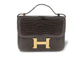 a brown and black handbag with a gold handle on a white background