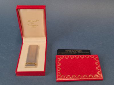 un briquet argenté dans une boîte rouge posée sur un fond bleu