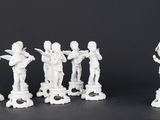 four white figurines are lined up against a black background