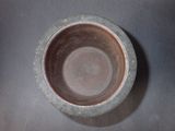 a brown bowl sitting on a table with a black background