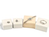 trois boîtes à bijoux blanches et une bague sur fond blanc