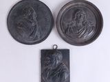 trois médaillons en bronze représentant un homme et une femme sur fond blanc