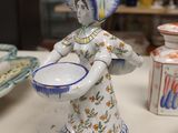 a figurine of a woman holding a bowl on a table