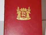 un livre rouge orné d'un blason doré