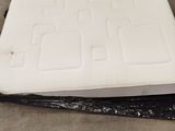 two white mattresses are sitting on top of a black plastic bag