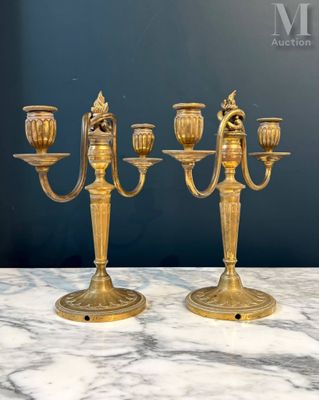 une paire de candélabres anciens en laiton posés sur une table en marbre