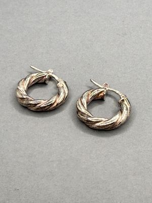 two pairs of silver hoop earrings on a gray surface
