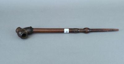 un gros plan d'une pipe avec un manche en bois posée sur une table