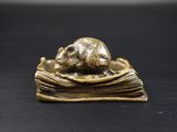 figurine en bronze représentant une souris posée sur un livre, sur un fond noir