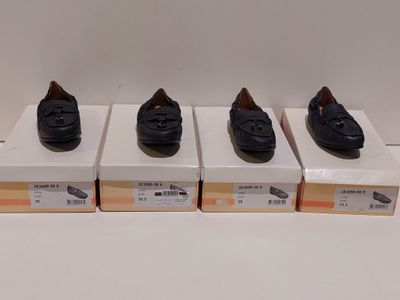 quatre paires de chaussures noires posées sur des cartons, sur une surface blanche