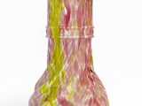 un vase rose et jaune posé sur une surface blanche