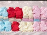 many pairs of baby mittens sitting on a blanket