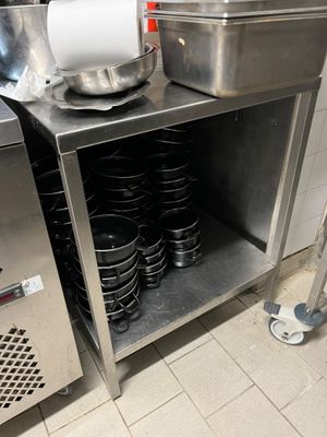 un plan de travail en inox sur lequel sont posés tout un tas de casseroles et de poêles
