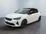 Une voiture blanche est garée dans une pièce au sol noir.