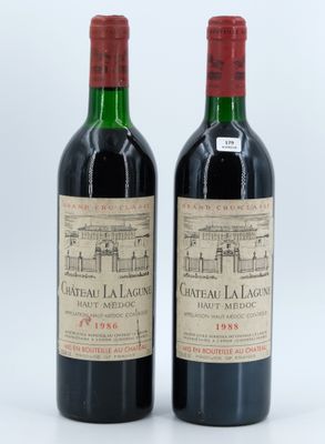 two bottles of red wine sitting next to each other on a white surface