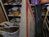 une étagère remplie de pots de peinture et de seaux dans une pièce