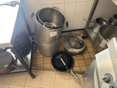 il y a beaucoup de casseroles et de poêles par terre dans la cuisine