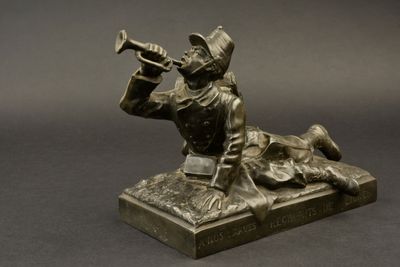 statue en bronze représentant un homme jouant de la trompette, posée sur une table