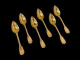 six gold spoons are lined up on a black surface