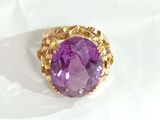 an image of a gold ring with a purple stone in it