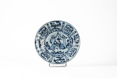 une assiette bleue et blanche posée sur un support sur une surface blanche