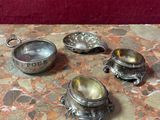 quatre plats en argent posés sur une table avec un fond rouge