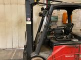 un chariot élévateur rouge garé dans un garage à côté d'un immeuble