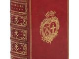 un vieux livre à la couverture rouge ornée d'un emblème doré