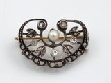 une broche ornée de perles et de diamants sur un fond blanc