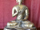 buddha statue sitting on a wooden table with a red background