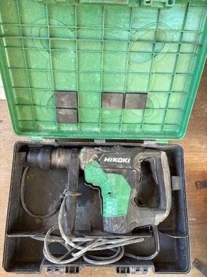 a green box with a drill in it on a wooden floor