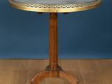 une petite table avec un plateau circulaire posé sur un piètement en bois