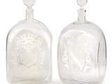 pair of clear glass bottles with etched crest and coat of arms on them