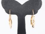 a pair of gold earrings on a black stand on a white background