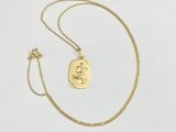 a gold necklace with a small coin on a chain