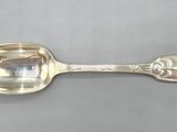 an antique silver spoon with a face on it sitting on a table