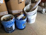 plusieurs seaux de peinture posés par terre à côté d'une pile de cartons