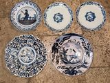 quatre assiettes bleues et blanches ornées de motifs, posées sur un sol carrelé