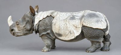 a sculpture of a rhino standing on a gray surface