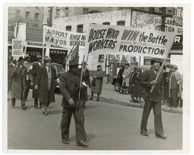 photo en noir et blanc d'un groupe d'hommes marchant dans une rue