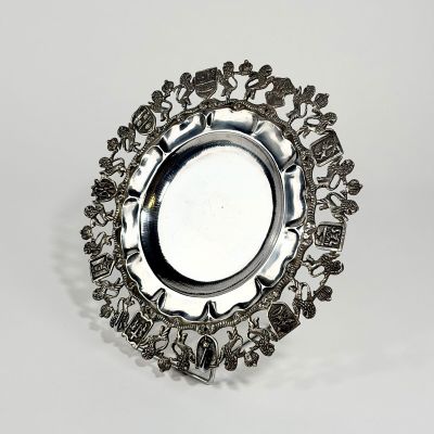 une plaque d'argent ornée d'un motif sur une surface blanche